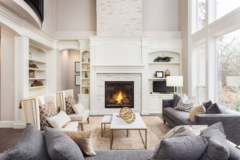 Beautiful living room interior with tall vaulted ceiling, loft area, hardwood floors and fireplace in new luxury home. Has large bank of windows Bright living room with neutral walls and large windows